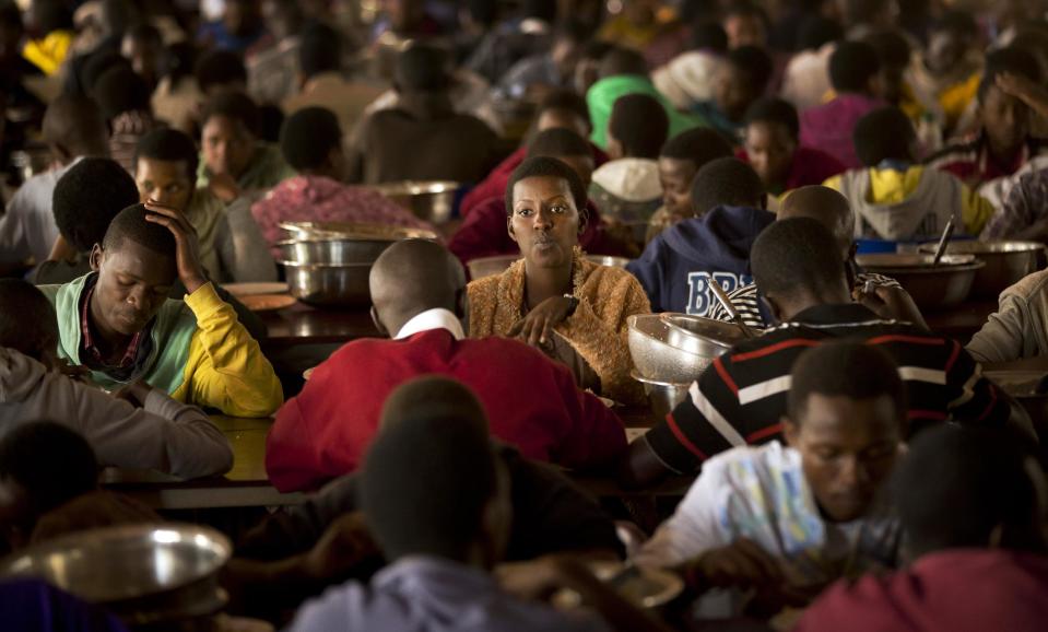 In this photo taken Monday, March 24, 2014, Rwandan students have lunch in the cafeteria at the Agahozo-Shalom Youth Village near Rwamagana, in Rwanda. Most of the kids in a school set amid the lush green, rolling hills of eastern Rwanda don't identify themselves as Hutu or Tutsi. That's a positive sign for Rwanda, which is now observing the 20th anniversary of its genocide, a three-month killing spree that, according to the official Rwandan count, left more than 1 million people dead, most of them Tutsis killed by Hutus. The teenagers attending the Agahozo-Shalom Youth Village, a school with dorms that creates tight-knit student families, say the ethnic slaughter that their parents or grandparents were a part of either as victims or perpetrators won't be repeated. The school director echoes the sentiment. (AP Photo/Ben Curtis)