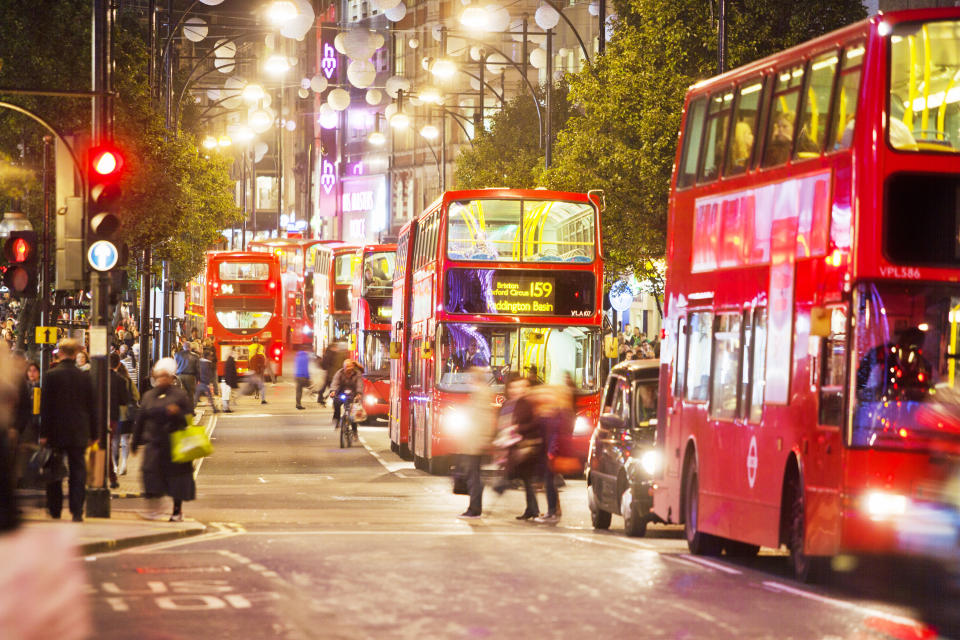 London, England - October 31, 2013: Lots of red busses are driving on the Oxford street in the heart of London, England. Pedestrians are walking on the pavements and are crossing the street which is famous for its shopping centres.