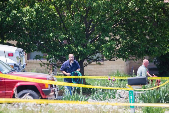 People unravel hoses at the scene of a triple homicide in Layton on Friday, May 19, 2023. | Ryan Sun, Deseret News