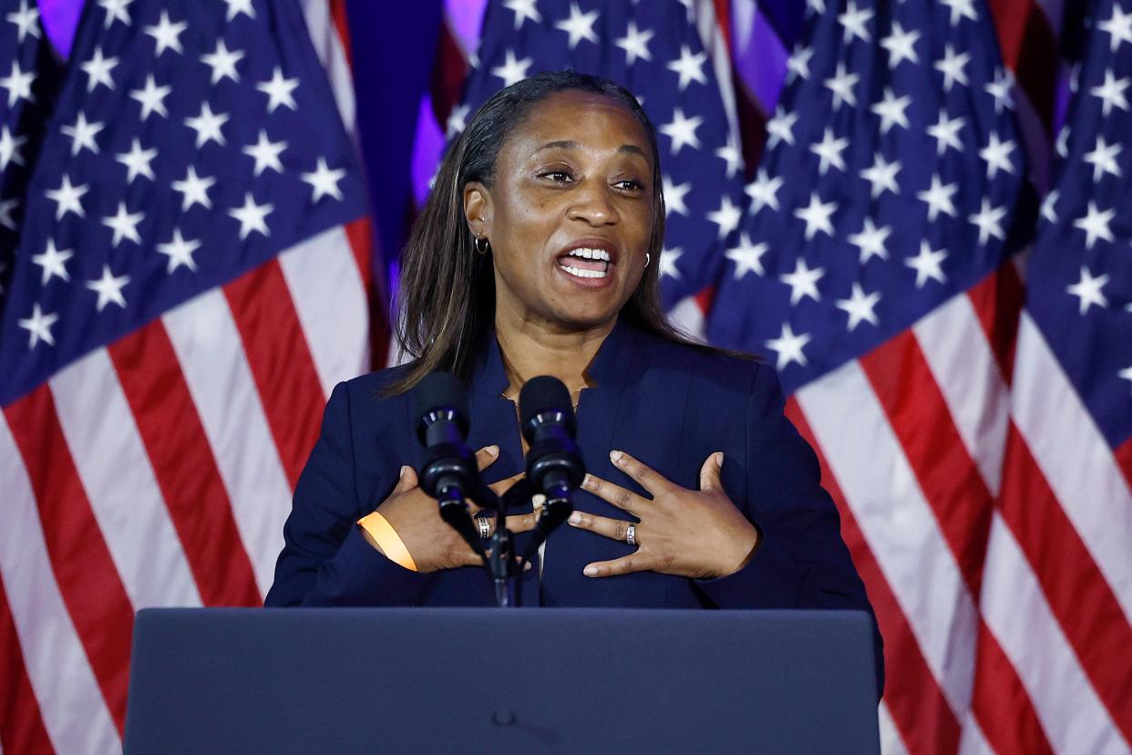 Butler speaks at a lectern with many American flags behind her.