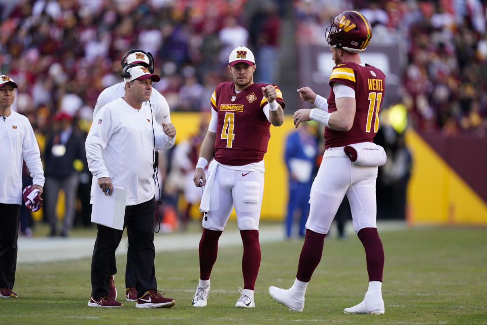 Washington Commanders backup quarterback Taylor Heinicke (4) fist bumps quarterback Carson Wentz (11) during the first half of an NFL football game against the Cleveland Browns, Sunday, Jan. 1, 2023, in Landover, Md. (AP Photo/Patrick Semansky)