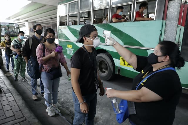 People have their temperatures checked before boarding a bus during the first day of a more relaxed lockdown that was placed to prevent the spread of the new coronavirus in Manila, Philippines