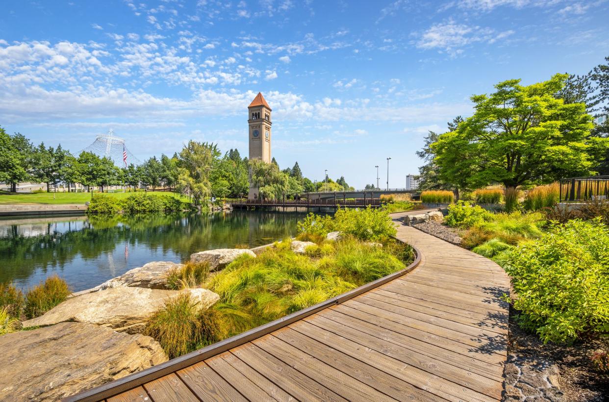 View from the Spokane River waterfront promenade path looking towards the expo pavilion and clock tower at the public Riverfront Park in downtown Spokane, Washington, USA.