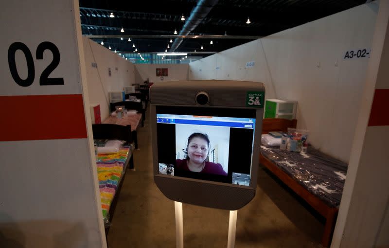 A volunteer who provides translation services for migrant workers is pictured on the screen of a "telepresence" robot at Changi Exhibition Centre which has been repurposed into a community in Singapore