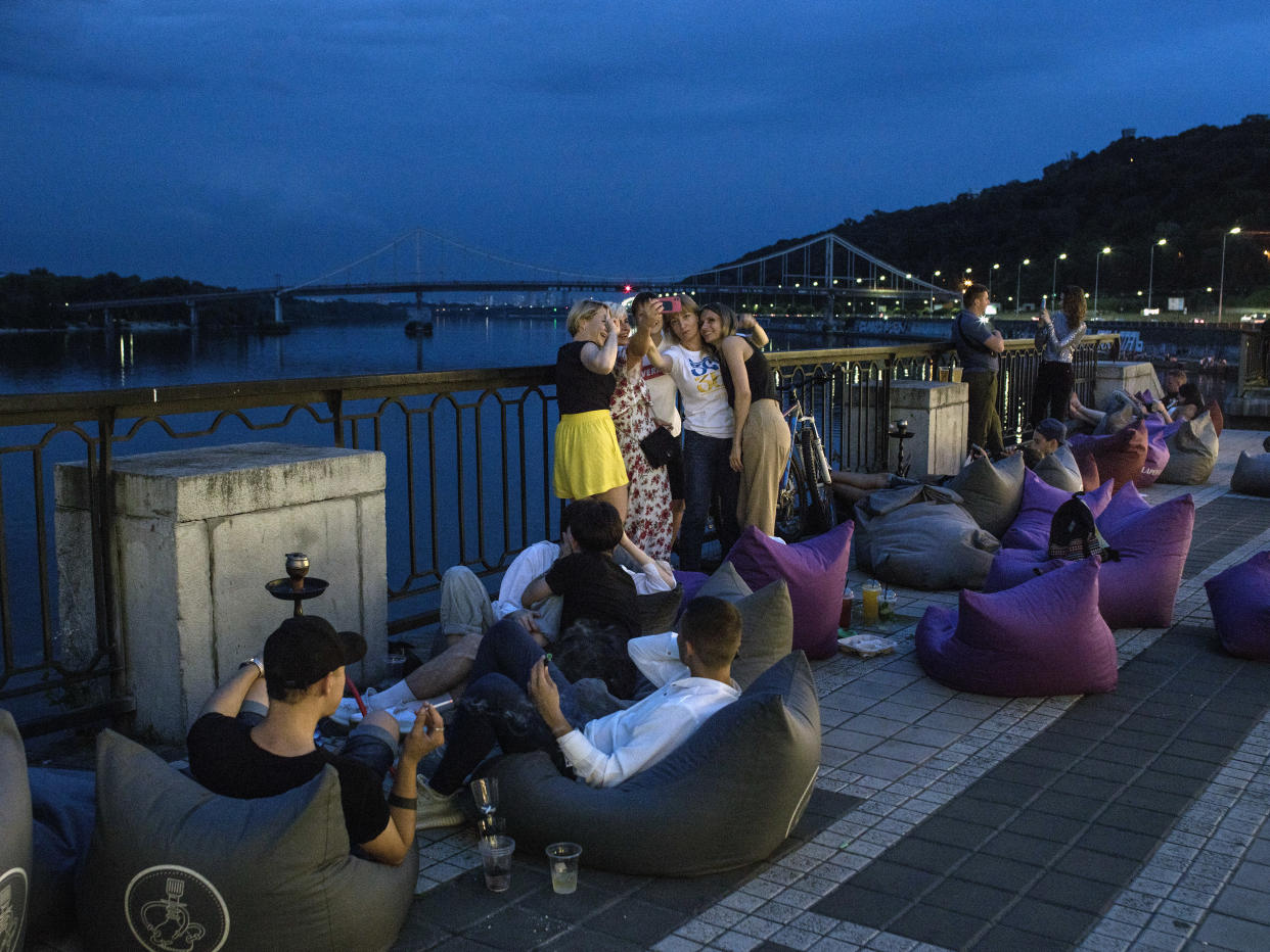 Los juerguistas disfrutan de su tiempo junto al río Dniéper media hora antes de que comience el toque de queda en Kiev el 16 de julio de 2022. (Laura Boushnak/The New York Times)
