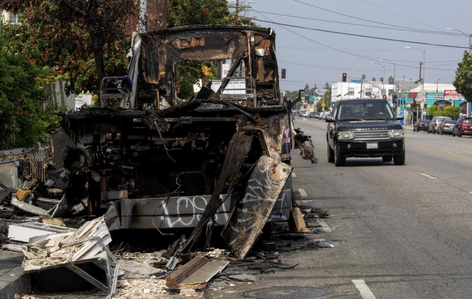 Burned out RV next to a car driving past.