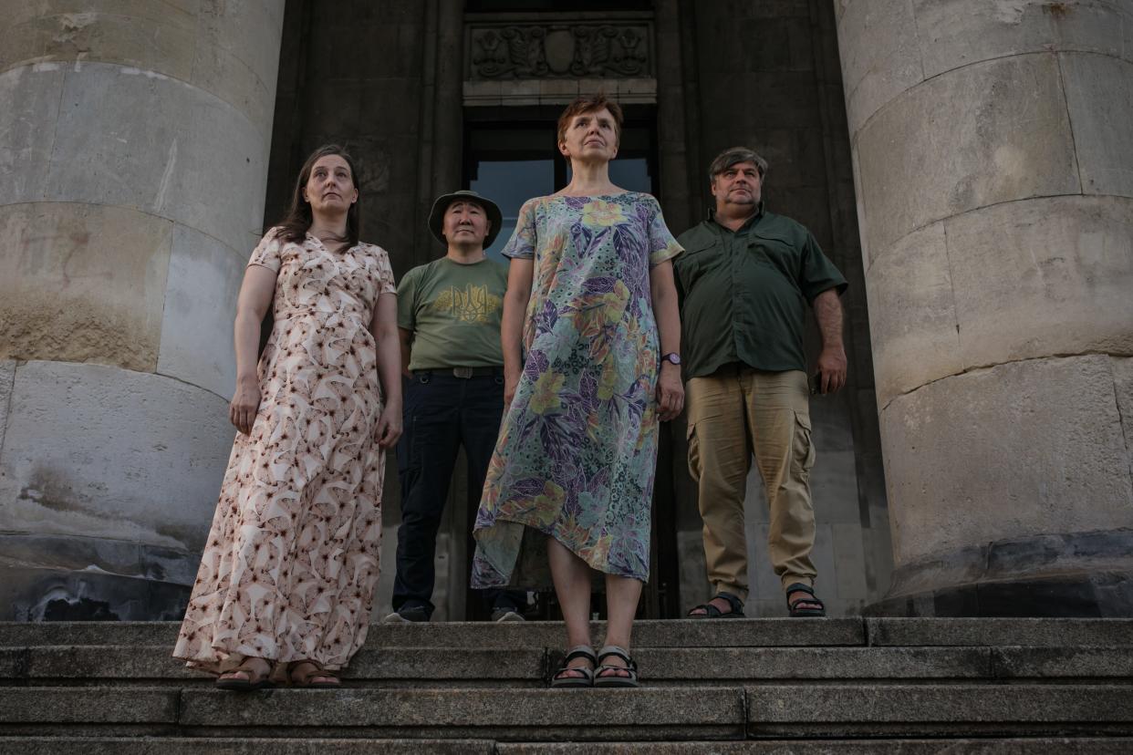 A group of people stand between two stone columns.