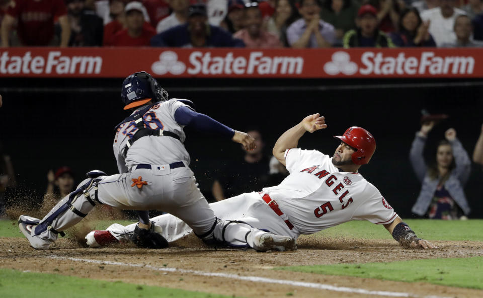 Los Angeles Angels' Albert Pujols, right, scores past Houston Astros catcher Robinson Chirinos after a double by Kevan Smith and a throwing error by Astros second baseman Jose Altuve during the seventh inning of a baseball game, Monday, July 15, 2019, in Anaheim, Calif. (AP Photo/Marcio Jose Sanchez)