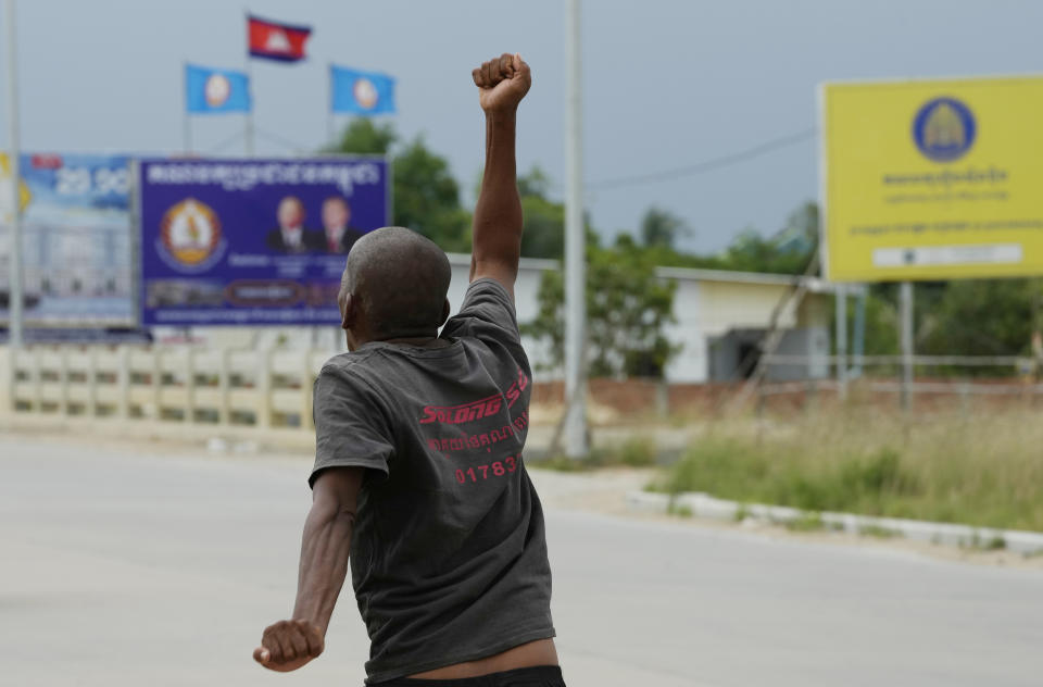 A Cambodian beggar runs for begging near political party posters including the National United Front for an Independent, Neutral, Peaceful and Cooperative Cambodia party (FUNCINPEC), upper right, and Cambodia People's Party (CPP), upper left, during a campaign rally period for the July 23 general election on the outskirts of Phnom Penh, Cambodia, Thursday, July 20, 2023. (AP Photo/Heng Sinith)