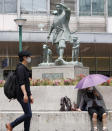 People wear face masks to help curb the spread of the coronavirus in front of Okayama railway station in Okayama, western Japan, Friday, May 14, 2021. Japan is set to further expand a coronavirus state of emergency, currently in Tokyo and five other prefectures, to nine areas, including Okayama, as the government is determined to hold the Olympics in just over two months. (Kyodo News via AP)