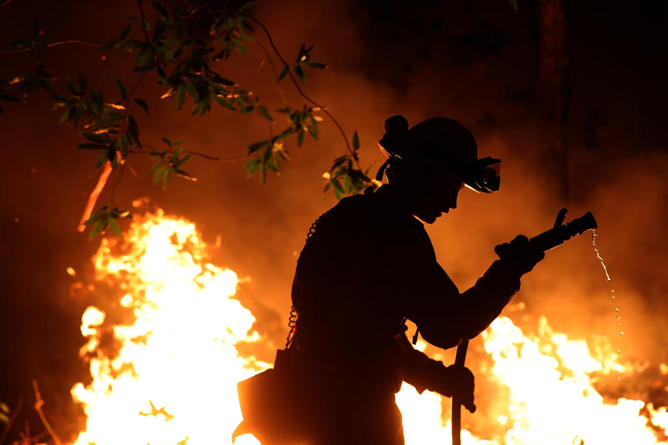 <p>CalFire firefighter Trevor Smith uses a hose as he monitors a firing operation while battling the Tubbs Fire on Oct. 12, 2017 near Calistoga, Calif. (Photo: Justin Sullivan/Getty Images) </p>