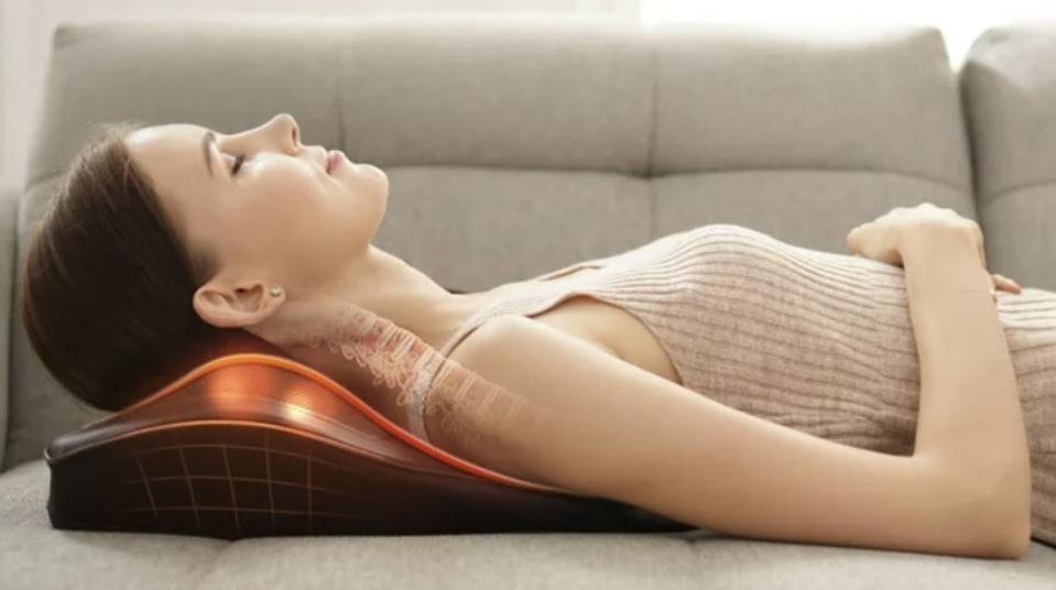 Person using a neck massage pillow on a couch. Product showcased for comfort
