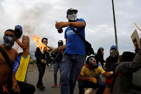 A demonstrator throws a molotov cocktail during clashes with riot police while rallying against Venezuela's President Nicolas Maduro in Caracas, Venezuela May 1, 2017. REUTERS/Carlos Garcia Rawlins