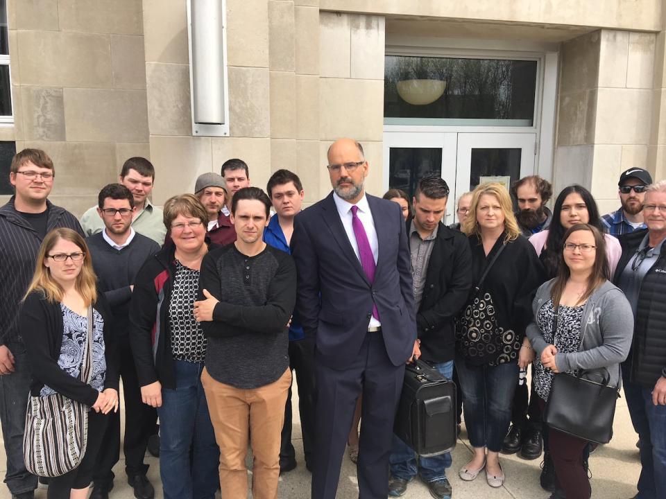 Dozens of people stand with defence lawyer (centre) Scott Cowan to show support for the accused. 