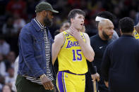 Los Angeles Lakers guard Austin Reaves (15) hold his throat as he is lead off the court by LeBron James, left, after Reaves was fouled resulting in a technical against the Houston Rockets during the second half of an NBA basketball game Wednesday, March 15, 2023, in Houston. (AP Photo/Michael Wyke)