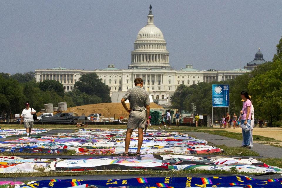 People visit the AIDS Memorial Quilt on display as part of the Smithsonian Folklife Festival on the National Mall in Washington, Thursday, July 5, 2012. An AIDS-free generation: It seems an audacious goal, considering how the HIV epidemic still is raging around the world. Yet more than 20,000 international HIV researchers and activists will gather in the nation's capital later this month with a sense of optimism not seen in many years _ hope that it finally may be possible to stem the spread of the AIDS virus. (AP Photo/Jacquelyn Martin)