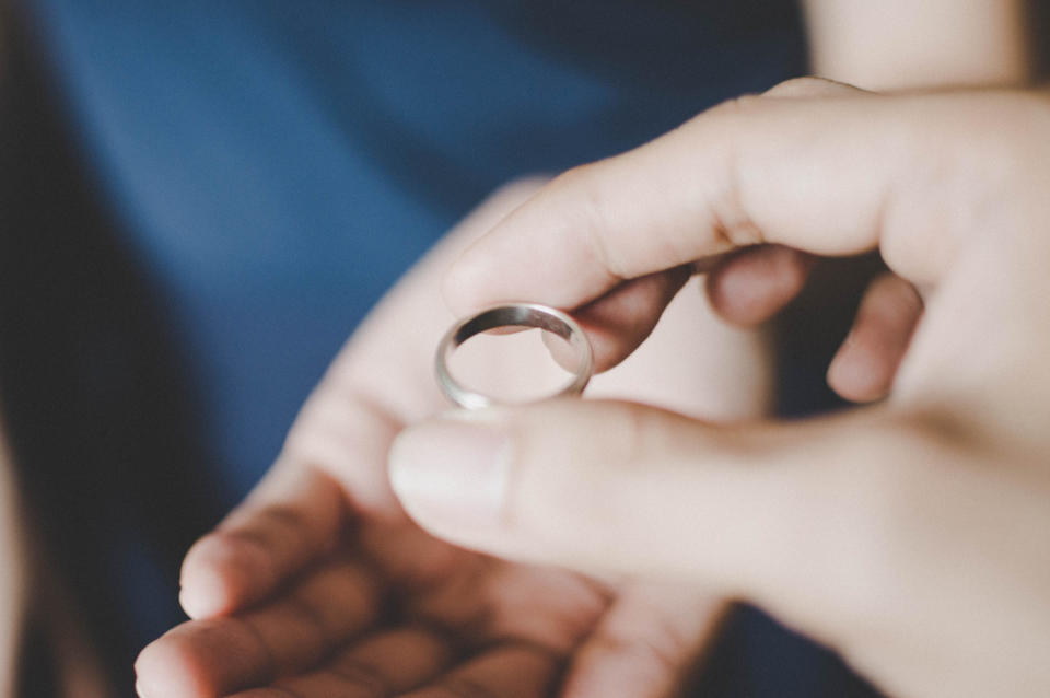 A hand holds a ring above another open hand, ready to receive it. No names provided