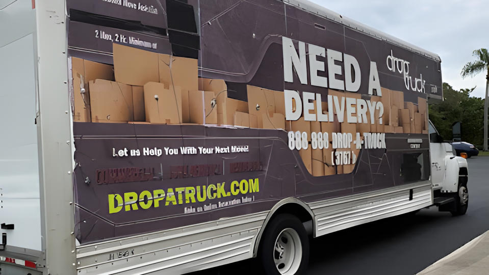 A Drop-a-Truck moving truck sits parked next to a curb