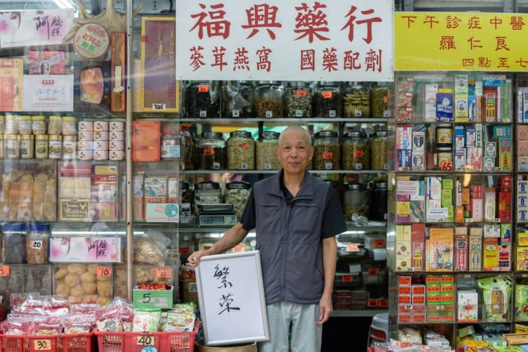 Chinese medicine shop owner Tan Kin Hua, 72, holds a board upon which he wrote Chinese characters to sum up his hopes for Hong Kong over the next 20 years. It says: 'Prosperity'