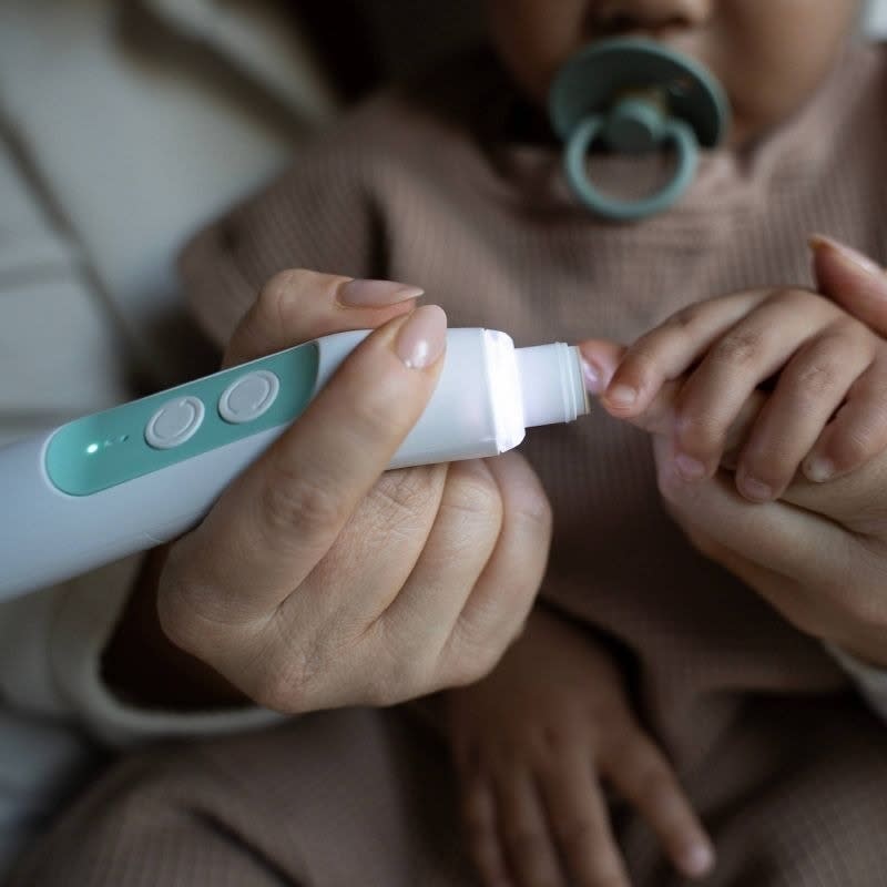 A nail buffer trims a baby's nails