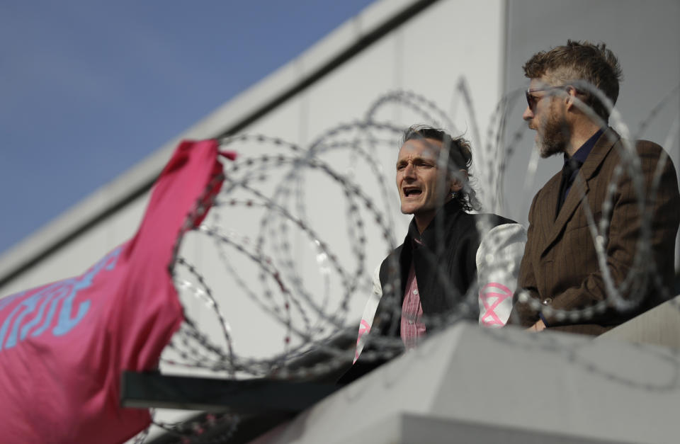 Extinction Rebellion demonstrators sing as they occupy a raised area at City Airport in London, Thursday, Oct. 10, 2019. Some hundreds of climate change activists are in London during a fourth day of world protests by the Extinction Rebellion movement to demand more urgent actions to counter global warming. (AP Photo/Matt Dunham)