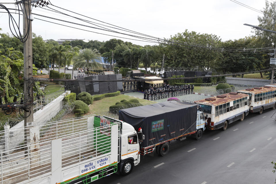 Police stand guard behind barbed wire and a row of large vehicles barricading the base entrance of the 11th Infantry Regiment, a palace security unit under direct command of the Thai king, as they await for the arrival of protesters Sunday, Nov. 29, 2020 in Bangkok, Thailand. Pro-democracy demonstrators are continuing their protests calling for the government to step down and reforms to the constitution and the monarchy, despite legal charges being filed against them and the possibility of violence from their opponents or a military crackdown. (AP Photo/Sakchai Lalit)