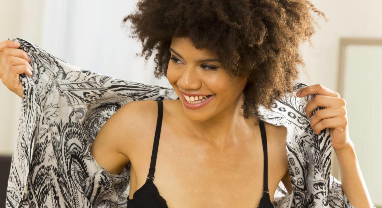 Smiling woman puts on shirt over bra 