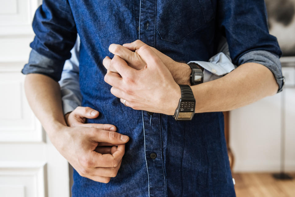 Close up shot of hands of a gay couple hugging. Focus is on their hands in front of their body. (Getty Images)