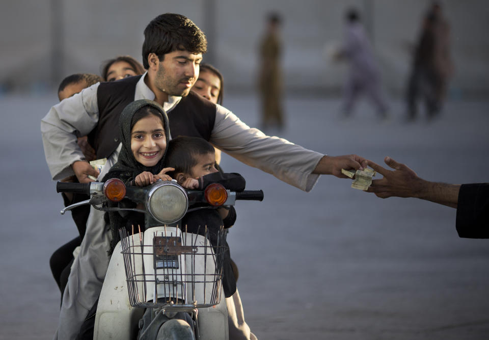 FILE - In this Friday, Nov. 1, 2013 file photo made by Associated Press photographer Anja Niedringhaus, an Afghan man with his five children on his motorbike pays money to enter a park in Kandahar, southern Afghanistan. Niedringhaus, 48, an internationally acclaimed German photographer, was killed and AP reporter Kathy Gannon was wounded on Friday, April 4, 2014 when an Afghan policeman opened fire while they were sitting in their car in eastern Afghanistan. (AP Photo/Anja Niedringhaus, File)