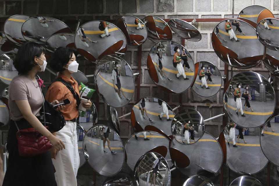 People wearing face masks to help protect against the spread of the coronavirus are reflected in mirrors at a subway station in Seoul, South Korea, Monday Aug. 31, 2020. South Korea has counted its 18th straight day of triple-digit daily jumps in coronavirus cases as its health minister warned about an increase in transmissions gone untraced.(AP Photo/Ahn Young-joon)