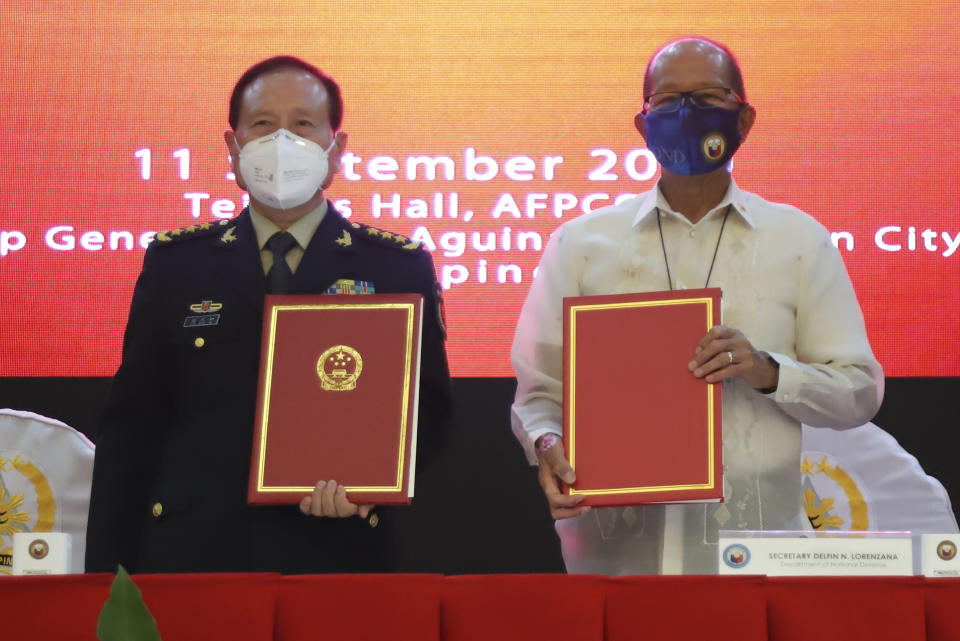 In this handout photo provided by the Department of National Defense Public Affairs Office (PAO), Philippine Defense Secretary Delfin N. Lorenzana, right, poses beside his Chinese counterpart General Wei Fenghe after the signing ceremony for donations in Humanitarian Assistance and Disaster Relief equipment from China at the Department of National Defense in Quezon city, Philippines, Friday Sept. 11, 2020. (Department of National Defense PAO via AP)