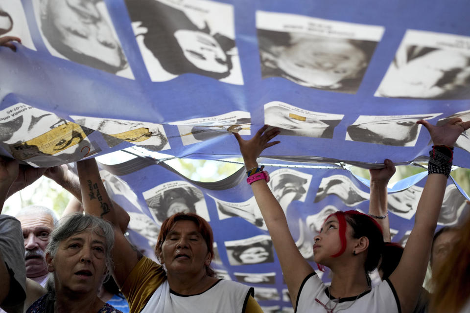 Demonstrators carry a banner with photos of people who disappeared during the 1976-1983 military dictatorship during a march commemorating the 48th anniversary of the coup in Buenos Aires, Argentina, Sunday, March 24, 2024. (AP Photo/Natacha Pisarenko)
