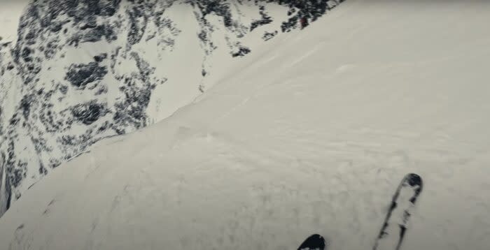 a pov looking down a steep slope with skis visible in the bottom of the frame