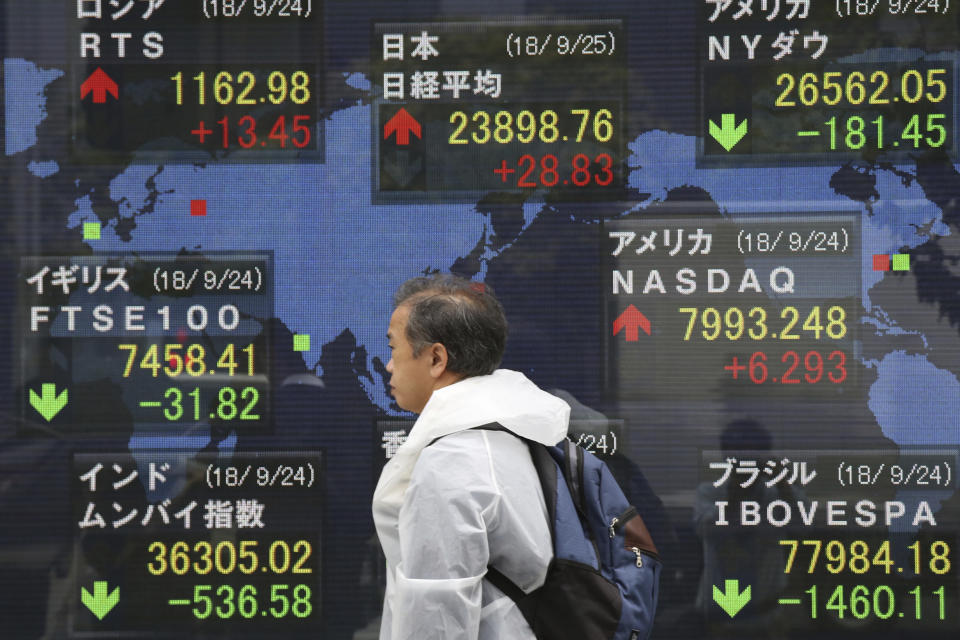 A man walks by an electronic stock board of a securities firm in Tokyo, Tuesday, Sept. 25, 2018. Asian stock markets were mostly lower Tuesday after a Chinese government report accusing the Trump administration of bullying other countries dampened hopes for a settlement in their escalating tariff war. (AP Photo/Koji Sasahara)