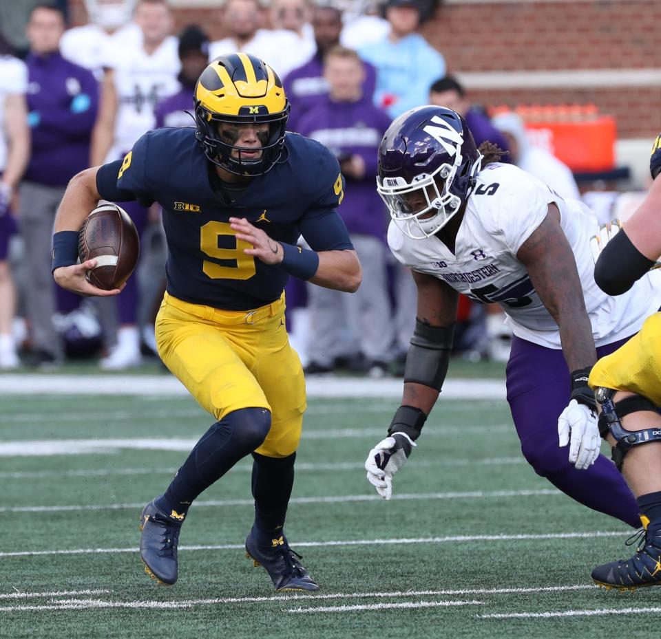 Michigan Wolverines quarterback J.J. McCarthy (9) runs by Northwestern Wildcats defensive lineman Jeffery Pooler Jr. (5) during second half action Saturday, Oct. 23, 2021 at Michigan Stadium.