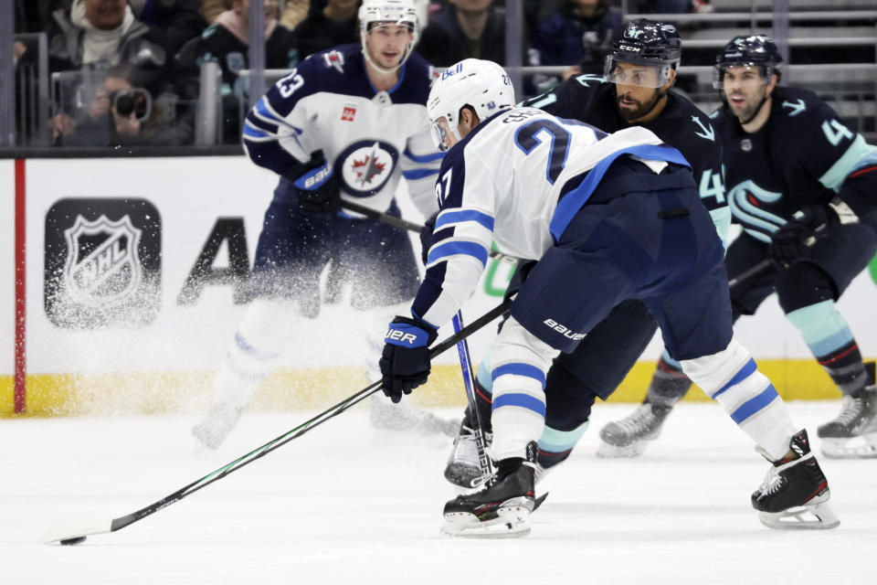 Winnipeg Jets left wing Nikolaj Ehlers (27) reaches for the puck with Seattle Kraken left wing Pierre-Edouard Bellemare (41) defending during the first period of an NHL hockey game, Friday, March 8, 2024, in Seattle. (AP Photo/John Froschauer)