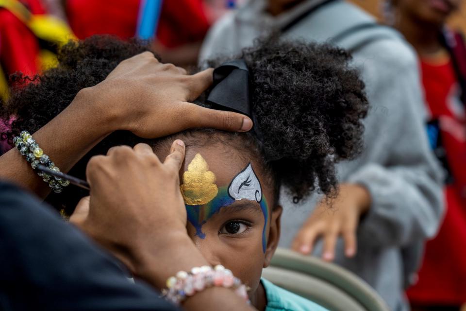 Kamryn Storr, of Canton, gets a design painted on her face along with other children from the Little Scholars Child Development Center during the Community Resource Fair at Christ the King Catholic School in Detroit on Aug. 18, 2023.