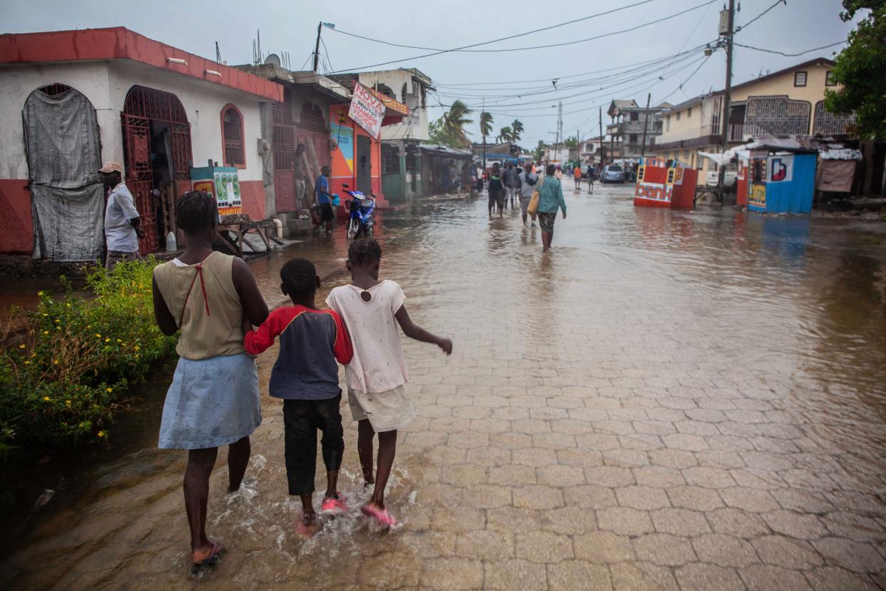 People walk through a flooded street as heavy rain brought by tropical storm Grace hits Haitians just after a 7.2-magnitude earthquake struck Haiti on Aug. 17, 2021, in Les Cayes, Haiti.