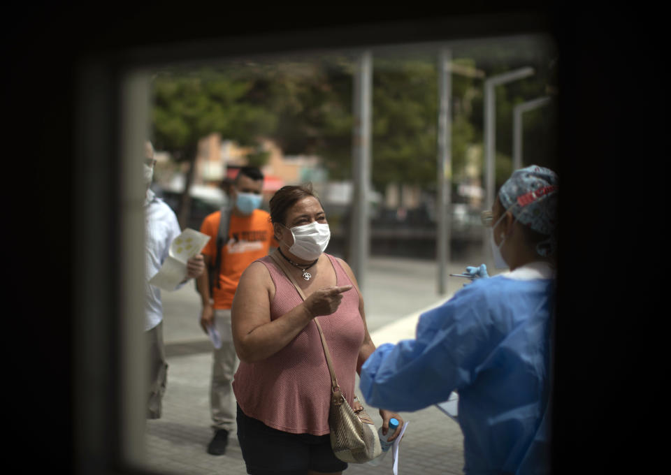 FILE - In this Tuesday, July 14, 2020 file photo, a health worker receives patients outside a local hospital in Hospitalet, outskirts of Barcelona, Spain. With the coronavirus rebounding in parts of Spain, it appears Catalonia and other regions have not adequately prepared to trace new infections in what was supposed to be an early detection system to prevent a new cascade of cases. (AP Photo/Emilio Morenatti, File)