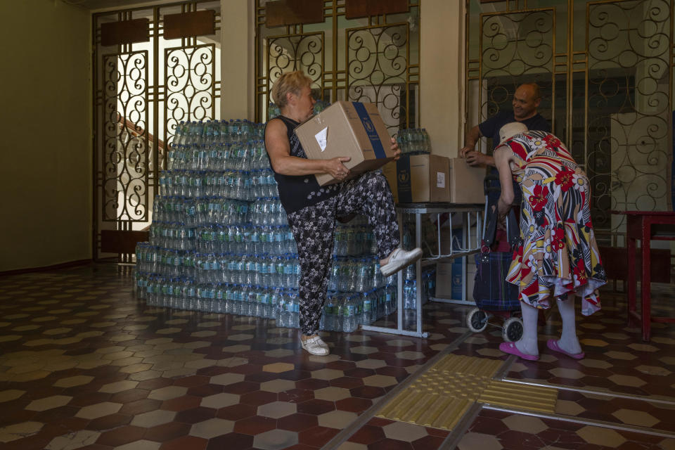 An elderly woman receives humanitarian food aid from the Kramatorsk city council, eastern Ukraine, Thursday, July 7, 2022. (AP Photo/Nariman El-Mofty)