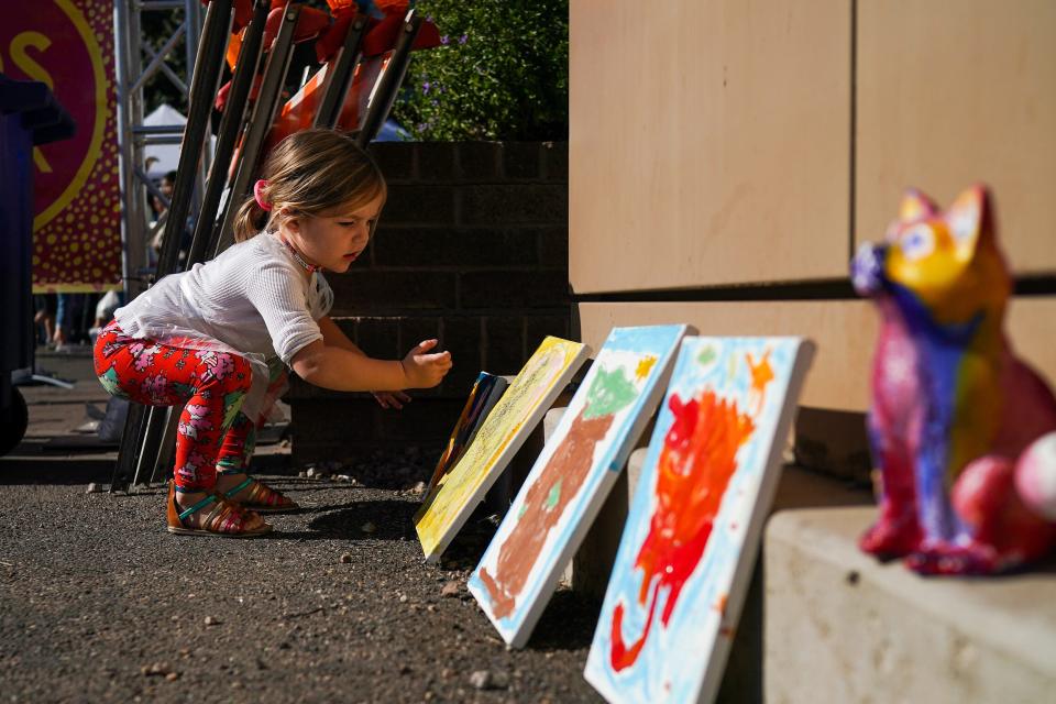 Jemma Hickman, 3, places her painting in the kids section at the Tempe Festival of the Arts on Saturday, Dec. 4, 2021, in Tempe.