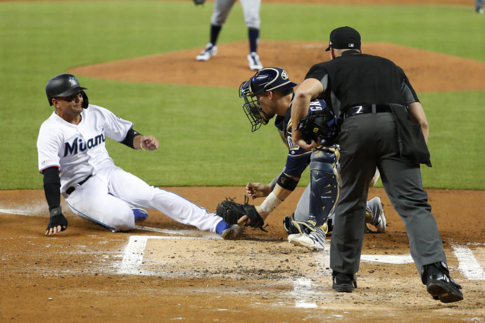 Milwaukee Brewers catcher Yasmani Grandal tags out Miami Marlins' Miguel Rojas at home plate as umpire Shane Livensparger looks on during the first inning of a baseball game, Thursday, Sept. 12, 2019, in Miami. (AP Photo/Wilfredo Lee)