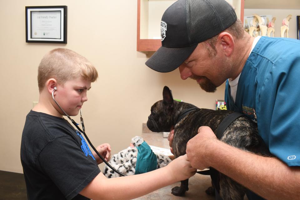 Dr. Bronk McDaniel, veterinarian at Montgomery Animal Hospital + Hotel, instructs Timothy Farr, 11, on how to listen to the heartbeat of a real French bulldog using a stethoscope. as On Saturday, the clinic invited children to "Future Vet Day"  where they learned about being a veterinarian.