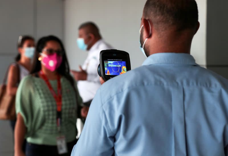 An employee measures the temperatures of travelers at the Tocumen International Airport during the coronavirus disease (COVID-19) outbreak, in Panama City