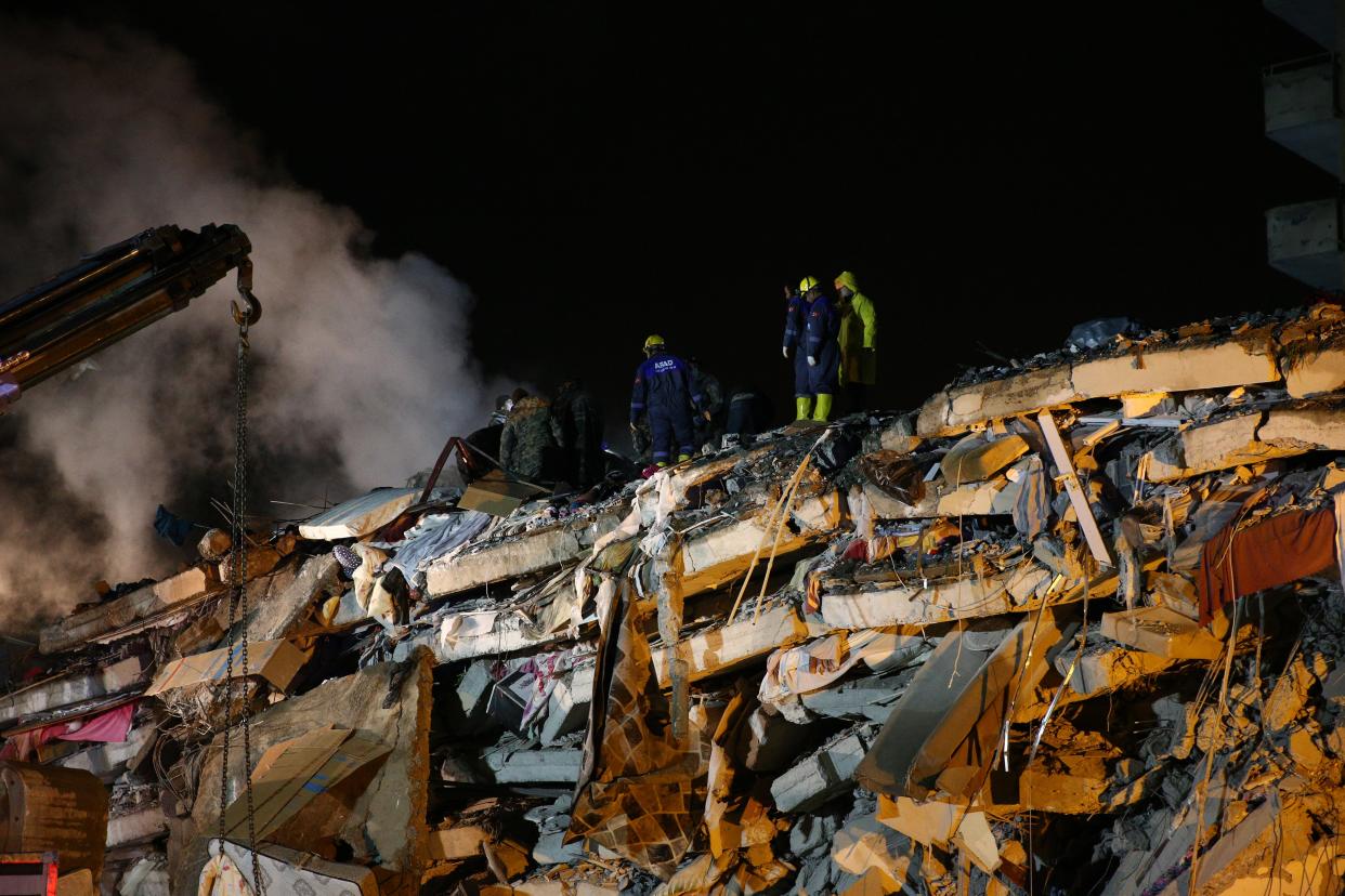 Rescuers stand on the wreckage of a building flattened by yesterday’s earthquake (Anadolu Agency/Getty)