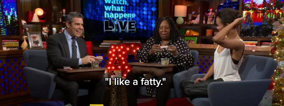 Andy Cohen learning how to roll a joint from Whoopi Goldberg while Zoe Saldana watches