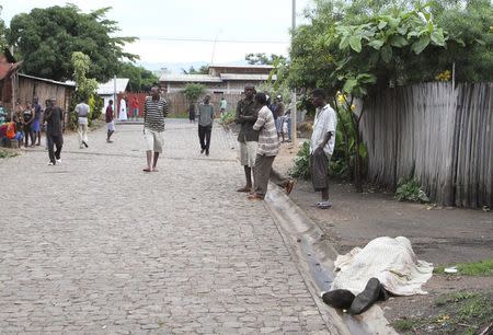 Residents look at the covered body of an unidentified man killed during gunfire, in the Nyakabiga neighbourhood of Burundi's capital Bujumbura, December 12, 2015. REUTERS/Jean Pierre Aime Harerimana