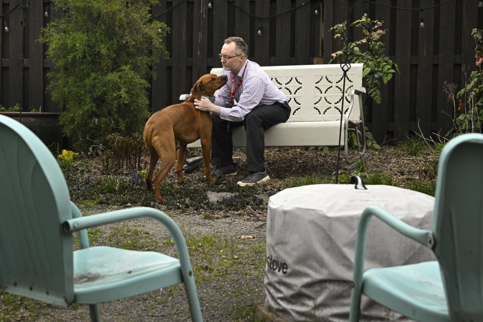 Chaplain Matthew Sullivan spends time with his dog Hank after coming home from work at The Covenant School Friday, March 22, 2024, in Nashville, Tenn. Nearly a year after a shooting at the christian elementary school that left six dead, many of the school's families have adopted dogs in dealing with their shared suffering. (AP Photo/John Amis)