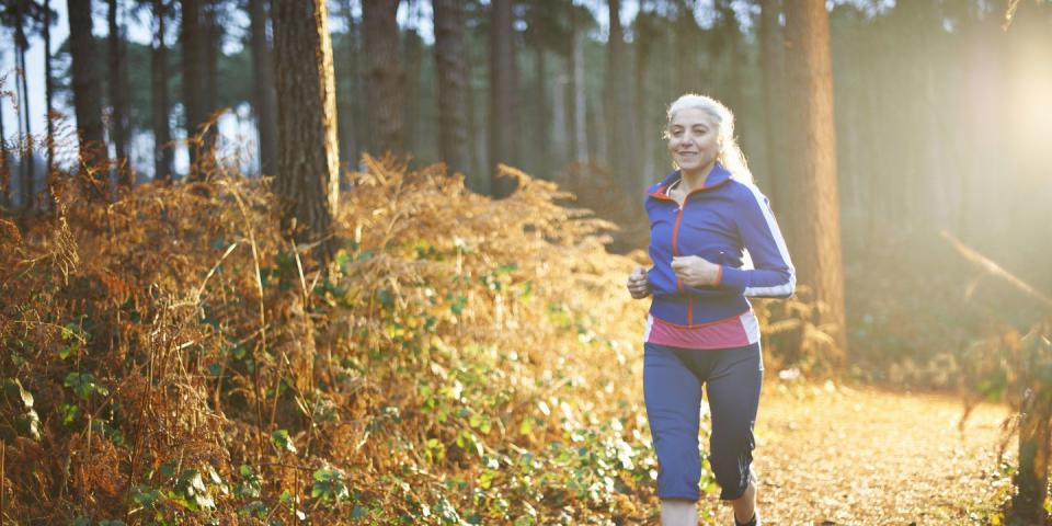 mature woman jogging on forest path