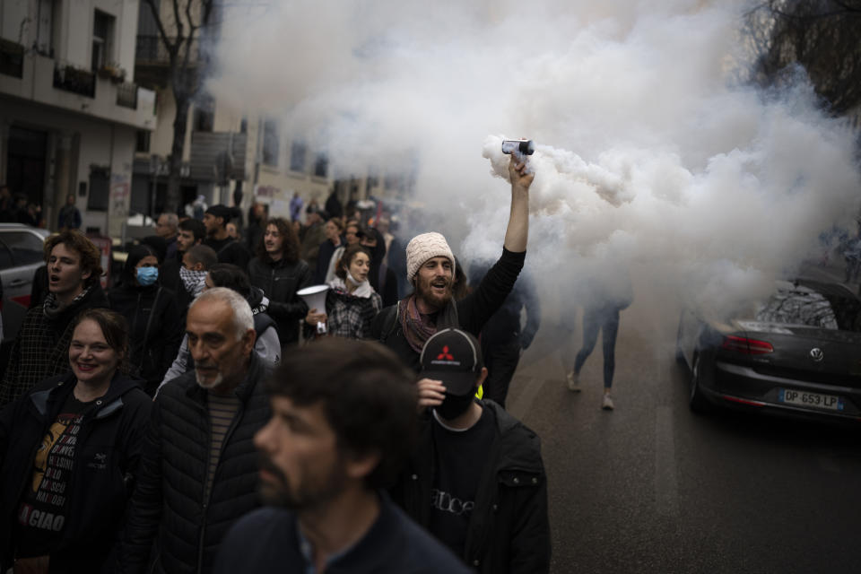 A protester raises a smoke canister during a demonstration in Marseille, southern France, Saturday, March 18, 2023. A spattering of protests are planned to continue in France over the weekend against President Emmanuel Macron's controversial pension reform. (AP Photo/Daniel Cole)
